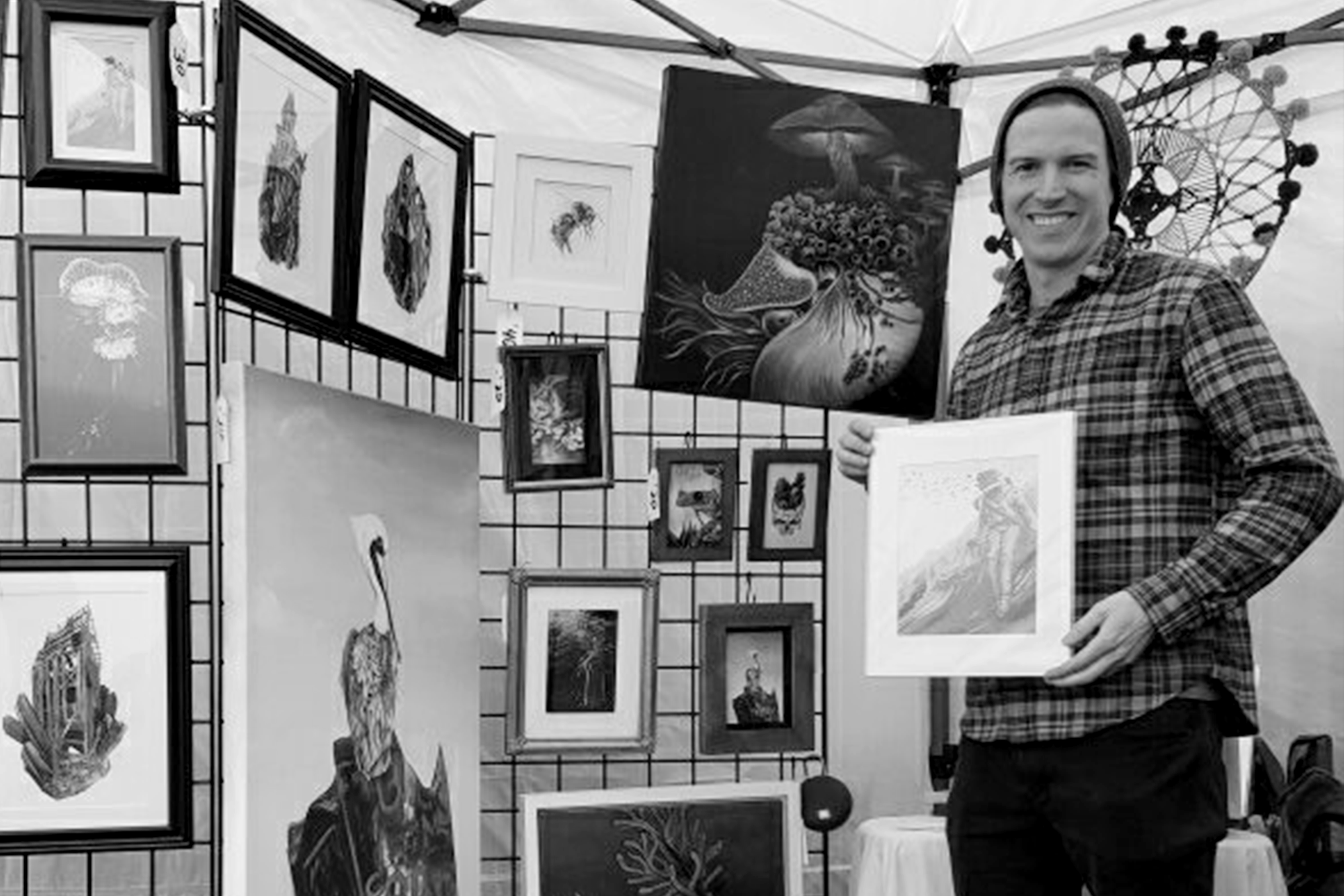 Ryan Breault standing next to artwork at a local market
